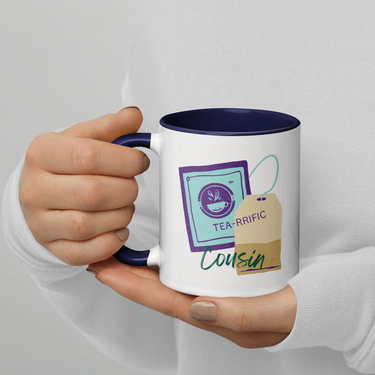 Hand holding a mug with tea-themed graphics and "TEA-RIFFIC Cousin" text on a plain White background.